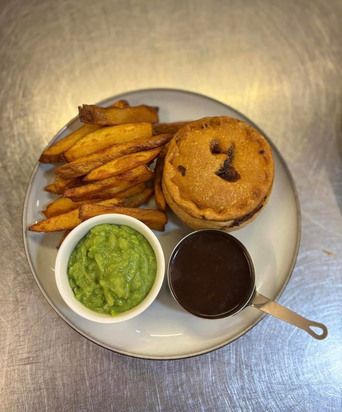 Homemade pie with chips, mushy peas and gravy