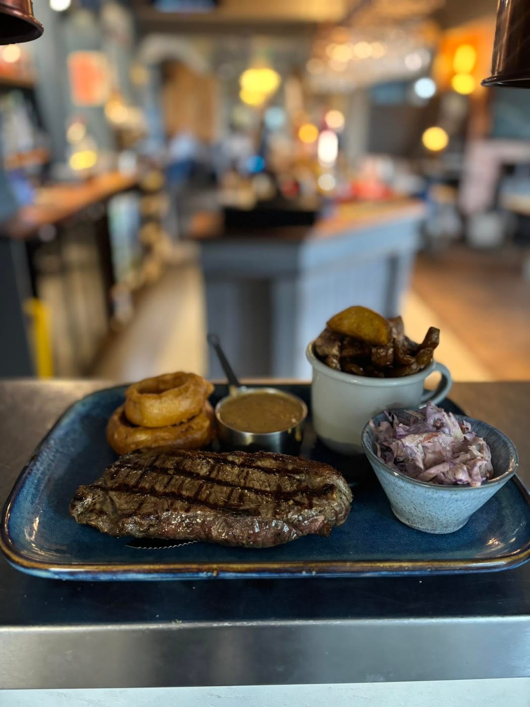 Char-grilled steak with onion rings, chips and peppercorn sauce